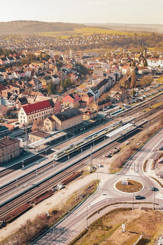 Aerial view of a city with railroad tracks and an intersection under bright sunlight, Mühlacker, Enzkreis, Germany
