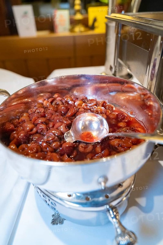 Silver bowl with red fruit and a large serving spoon on a table, Europäischer Hof, Königsbach Stein, Germany