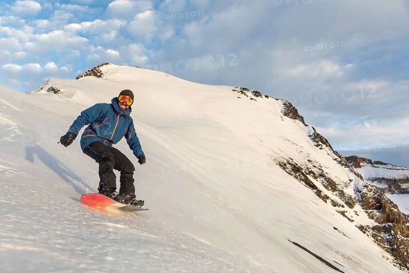 A snowboarder skillfully glides down a pristine snowy mountain slope, showcasing the thrill of winter sports under a clear, expansive sky