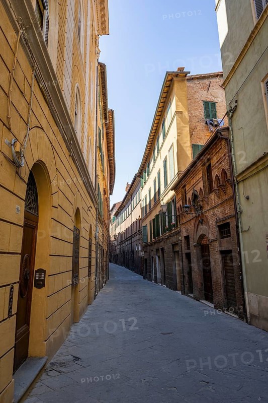 View of a small street going through old buildings in the city of Siena, Tuscany, Italy