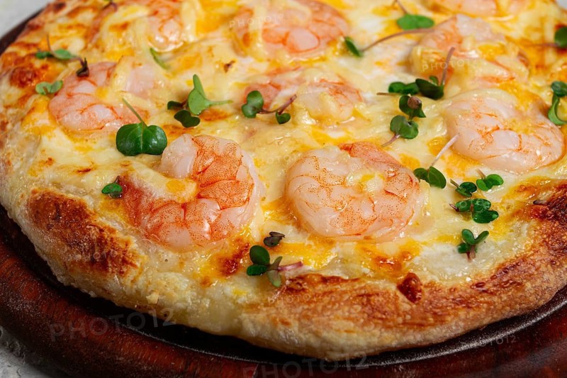 Four cheese pizza with shrimp and fresh microgreens, served on a wooden board, homemade, no people