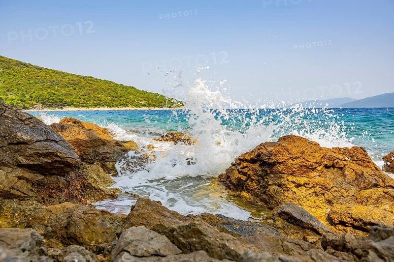 Wellen brechen an einem Felsen im Meer an einem sonnigen Tag auf der Insel Cres, Kroatien