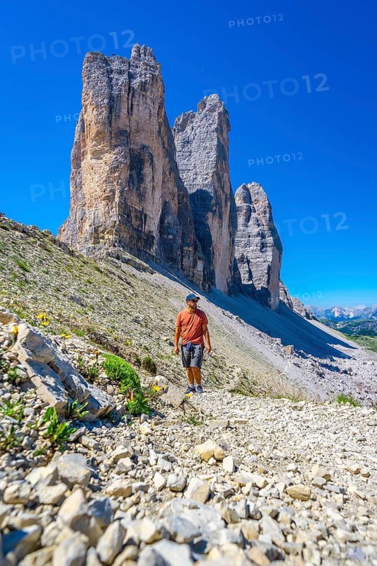 Tourist walking on the trail leading to the tre cime di lavaredo, enjoying the breathtaking view of the dolomites in summer