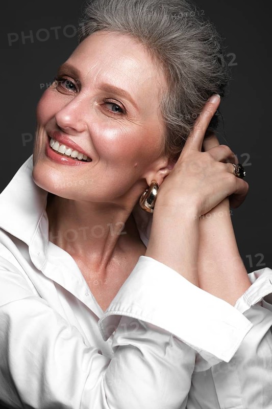 Portrait of a beautiful elderly woman in a white shirt with classic makeup and gray hair