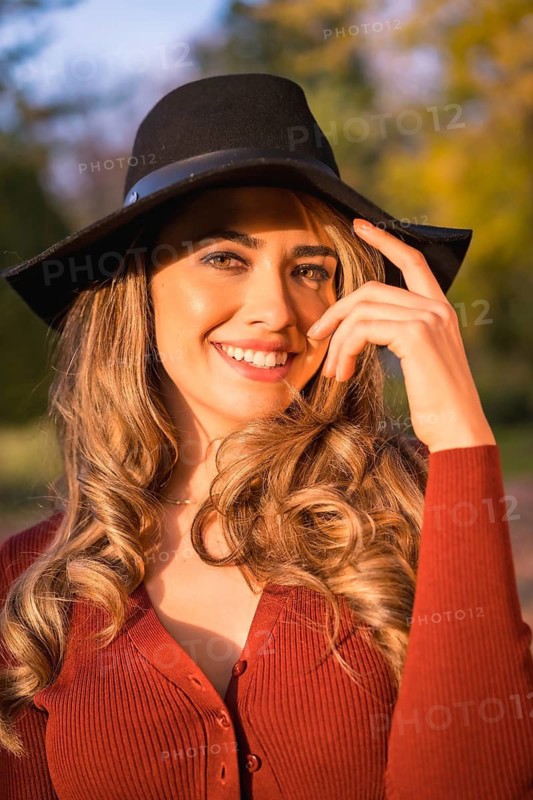 Lifestyle, portrait of a caucasian girl in a black hat at sunset in a green park
