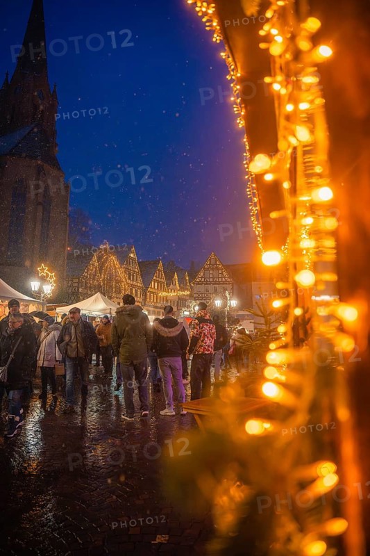 Festively illuminated Christmas market in historic old town with crowds of people on a rainy evening, Christmas market Calw, Black Forest, Germany