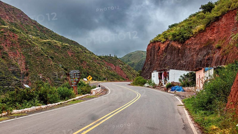 Empty street with houses in a mountainous, cloudy landscape, roads through the countryside of Quebrada de Cafayate near Salta in Argentina