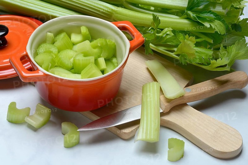 Celery stalks, pieces in pots with kitchen knife