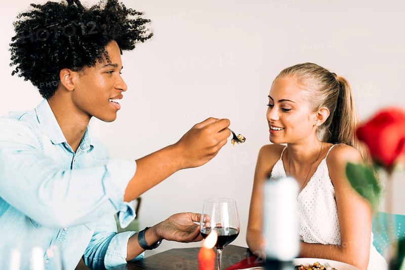 A couple enjoys a romantic dinner, sharing food and conversation over glasses of wine. The warm ambiance highlights their connection and the special moment