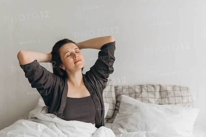 A serene morning moment with a woman relaxing in bed, embodying wellness and self-care. This image captures a peaceful start to the day, promoting a healthy lifestyle