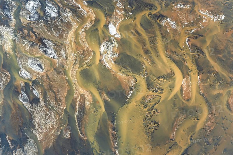 Aerial view of Iceland showcasing mesmerizing, abstract river patterns and unique textures. Natural beauty is captured in the intertwining shapes and earth tones