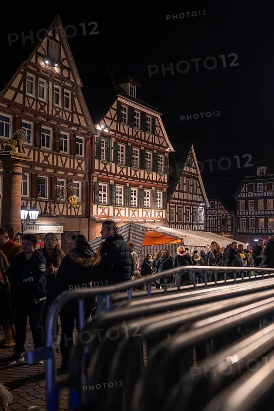 Crowd gathers at night in front of illuminated half-timbered houses and barriers, carnival, Calw, Black Forest, district of Calw, Germany