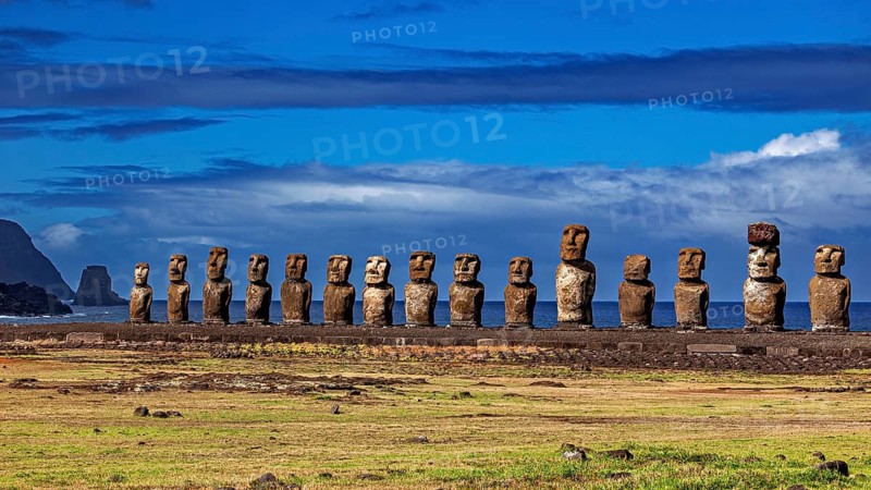 Moai statues on a grassy plain overlooking the sea under a cloudy sky, The Moai statues on Easter Island in the Pacific Ocean