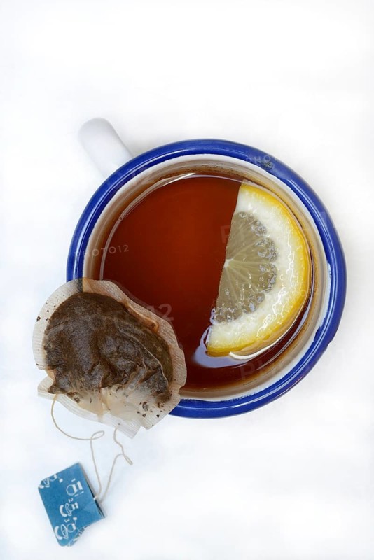 Black tea in cup with lemon slice and infusion bag