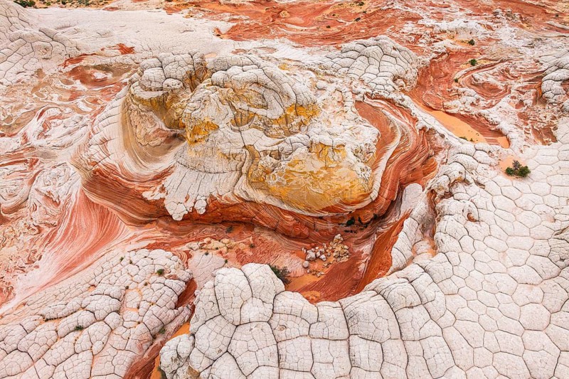 Captivating aerial view of abstract red and white rock formations in a desert landscape, showcasing intricate patterns and textures formed by geological processes