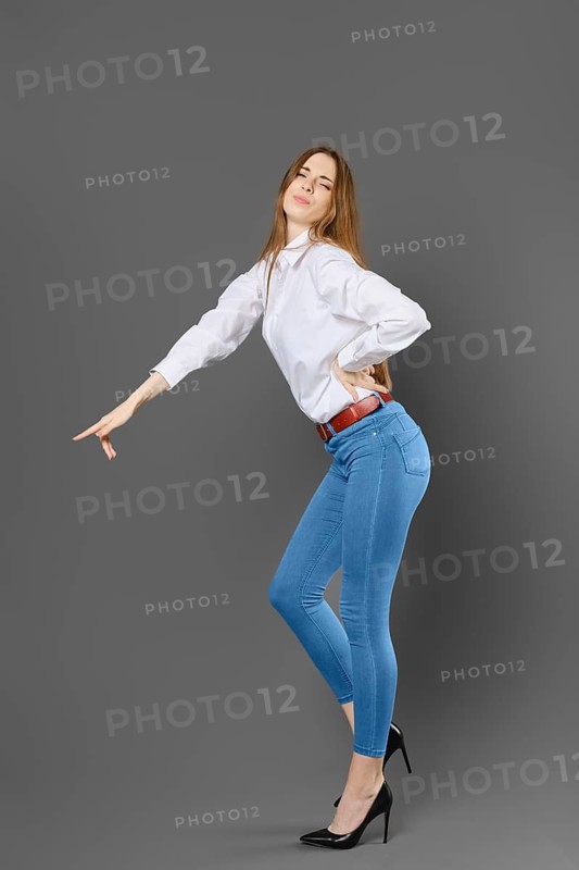 Naughty woman in white shirt and blue jeans pointing at something with her finger
