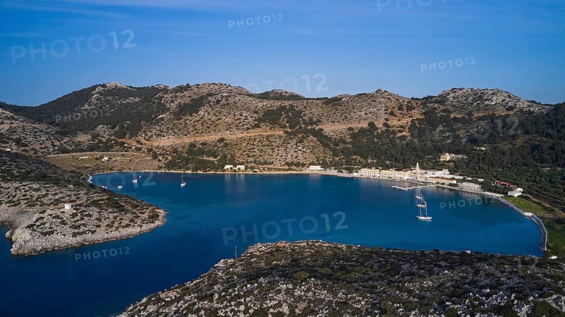 Drone shot, Picturesque bay with sailing boats and surrounded by rocky mountains, Holy Week, Bay of Panormitis, Panormitis Monastery, Symi, Dodecanese, Greek Islands, Greece