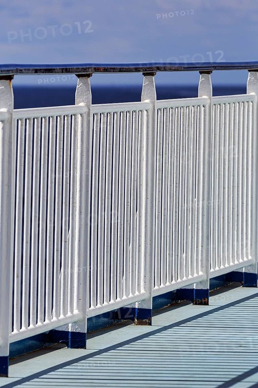 Sturdy railing, railing on the outer deck of a ferry, vertical bars, continuous handrail, safety, shadow casting, open sea, blue sky, minimalistic presentation, Gotland, Kalmarsund, Sweden