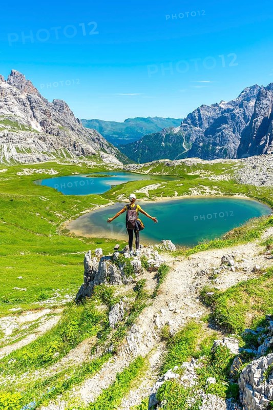 Female hiker with open arms savoring the stunning view of tre cime di lavaredo and alpine lakes in the italian dolomites. Laghi dei Piani