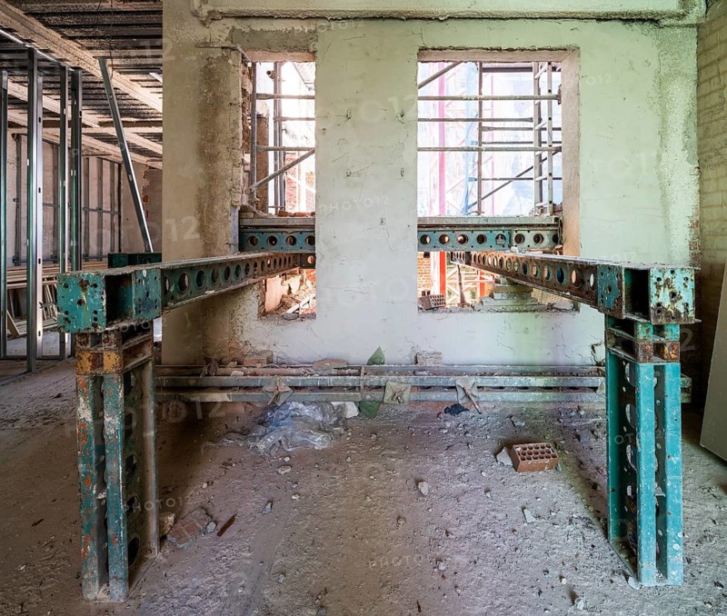 Interior view of a building under renovation. Visible scaffolding and steel beams support walls in this construction site, highlighting the transformation process