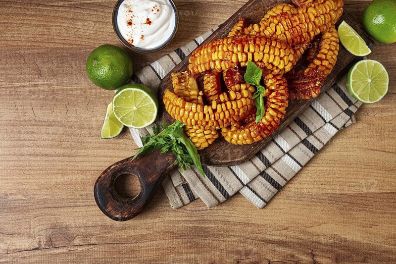 Corn ribs, with cream sauce, spices and lime, appetizer, on a wooden cutting board, homemade, no people