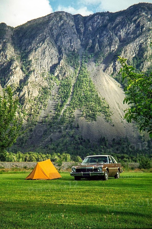 Dodge Aspen car parked in campsite by small two-man tent with mountain in background, unspecified location Rocky Mountains, north west USA 1977