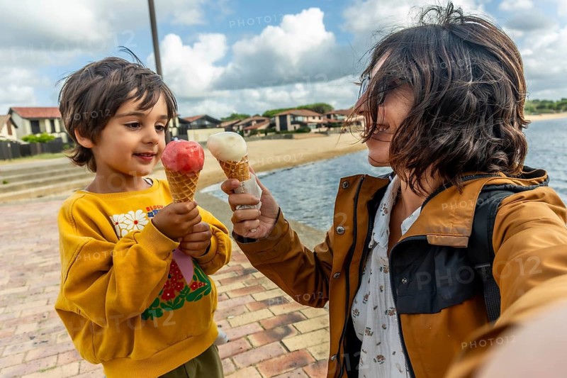 Mother and son holding ice cream cones, happily sharing a sweet moment together during their family holiday in vieux boucau les bains, france, by the water
