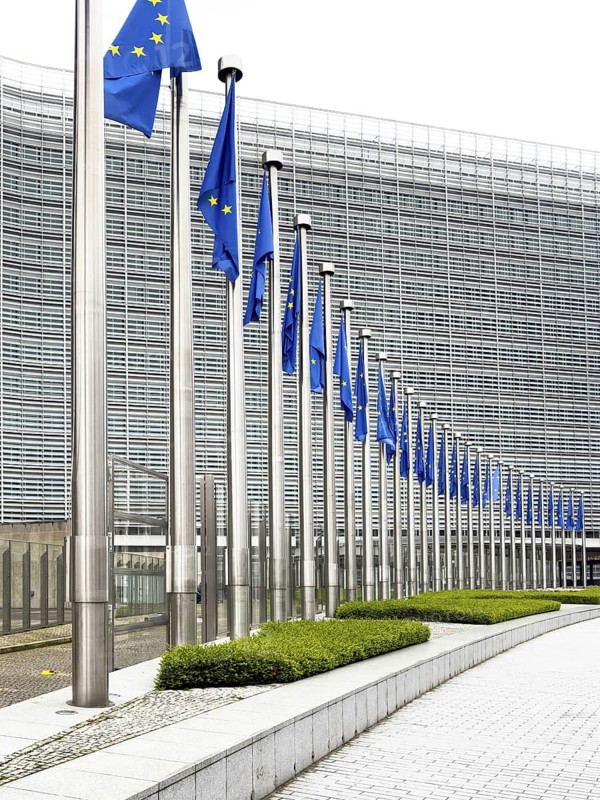 Long row of EU flags in front of the modern glass façade of the Berlaymont building, European Commission headquarters, Brussels, Belgium