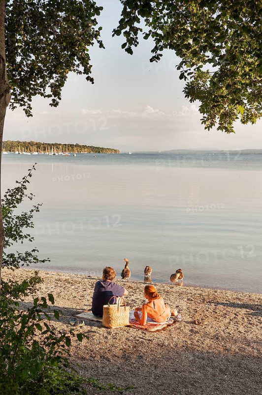 Couple sunbathing on the water, Herrsching am Lake Ammer, Bavaria, Germany