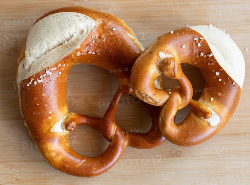 Two pretzels, one craft. Tradition served on a wooden board. A small and a normal pretzel from a traditional baker from Germany