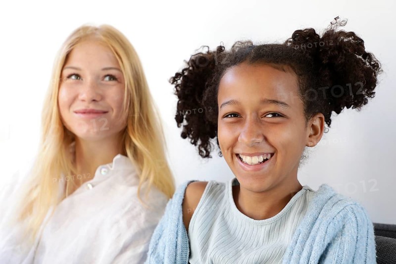 A cheerful close-up portrait of two smiling friends in a bright setting, exuding happiness and warmth. Their joyful expressions radiate genuine positivity and friendship