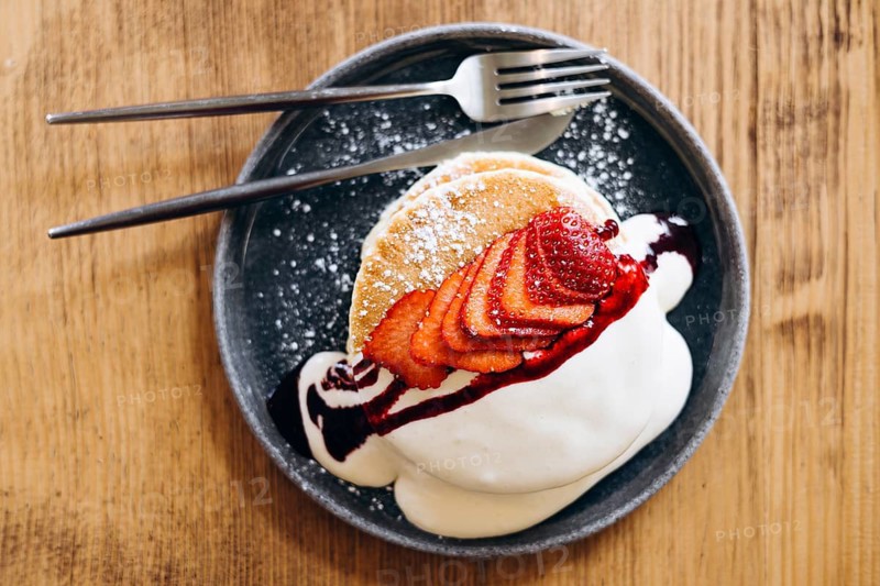 Indulge in fluffy japanese pancakes topped with fresh, juicy strawberries and a dollop of whipped cream. Drizzled with syrup and dusted with sugar, perfect for a delicious breakfast
