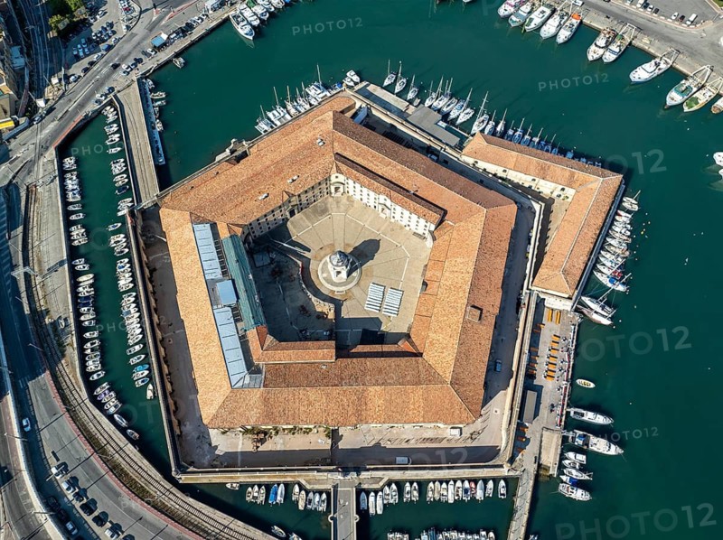 Drone captures of the pentagonal Lazzaretto of Ancona surrounded by harbor waters and boats. This historic Italian quarantine station now serves cultural and civic functions in the city