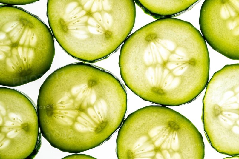 Close up of fresh cucumber slices displayed in a vibrant and visually appealing pattern. The translucent green color highlights the refreshing and healthy nature of cucumbers