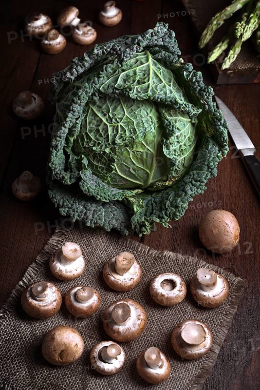 A fresh cabbage sits alongside mushrooms on a rustic wooden table, creating a natural and earthy composition. Perfect for food, vegetables or organic lifestyle themed visuals
