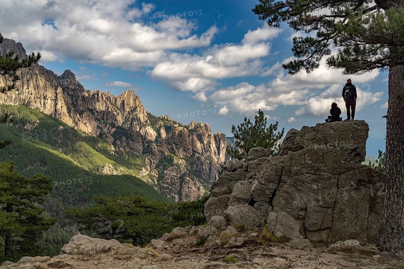 Tourists look out at the Bavella Needles mountain range or Aiguilles de Bavella, Corsica, France from the Col de Bavella Pass