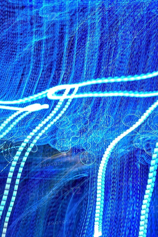 Swirling patterns of blue and white lights create an enchanting atmosphere, conveying a sense of movement and energy in an abstract style. This captivating display plays with perception and rhythm