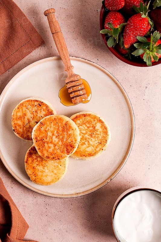 Cottage cheese pancakes with white sauce and strawberries, on a beige table, top view, selective focus, no people