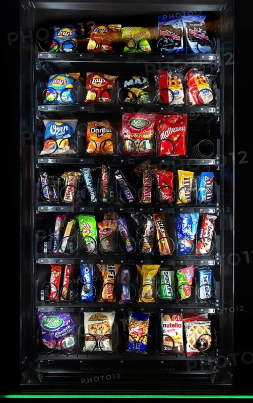 Snack vending machine, snack dispenser selling colourful sweets and chocolate bars in public place