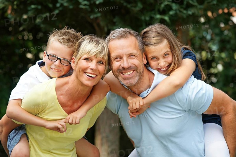 A happy family in the park, four people, man, woman, girl, boy, 8, 9, 35, 45 years piggyback, Hamburg, Federal Republic of Germany