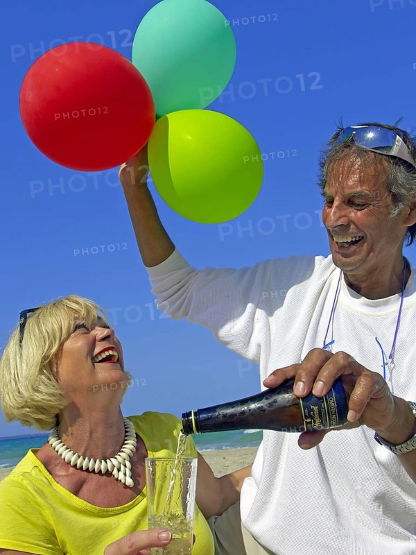 Seniors, couple on the beach in Ibiza, balloons, champagne, celebration, holiday joys