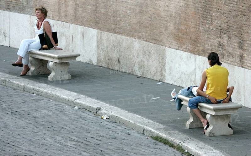 Rome, ITA, 08.09.2004 - A woman sits alone on a marble bench in Piazza del Popolo while a couple is resting on the opposite bench, ROME, Italy