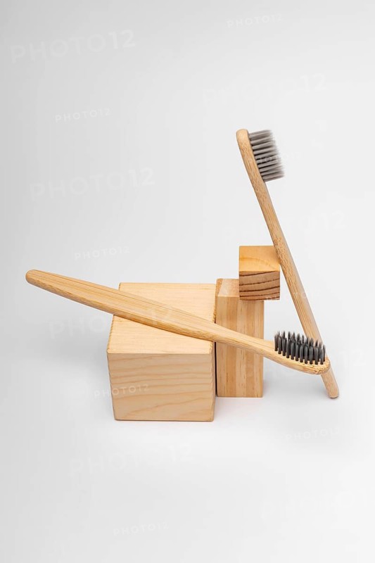 Eco-friendly bamboo toothbrushes resting on natural wooden blocks, highlighting a sustainable approach to dental care. Perfect for zero waste and reusable lifestyle enthusiasts