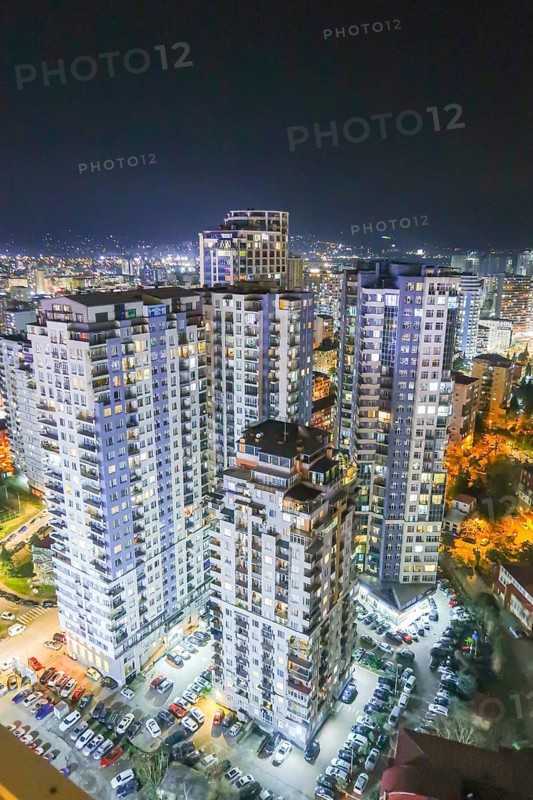 Stunning nighttime cityscape of Georgia showcasing modern high-rise buildings illuminated with vibrant lights, surrounded by a sprawling urban landscape under a clear night sky