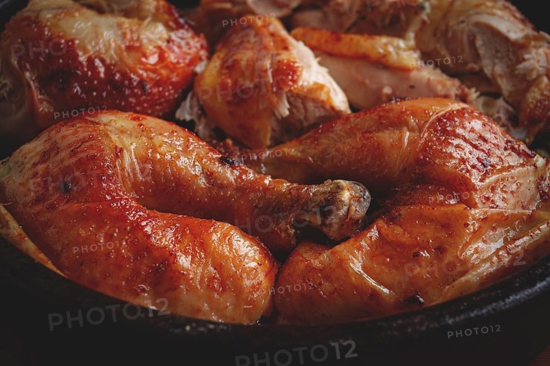 Grilled chicken pieces in a frying pan, wooden background, top view, homemade, no people