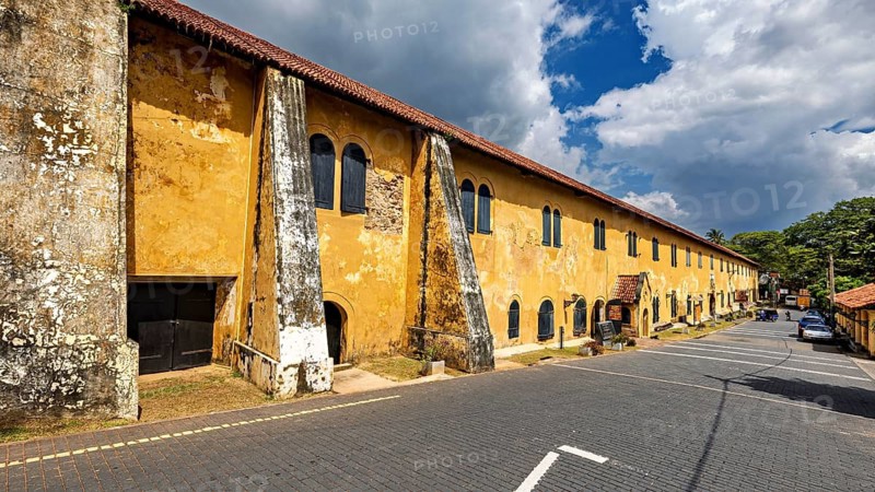 Long, old building with yellow façade and historic features under a cloudy sky, The historic downtown of Galle in Sri Lanka