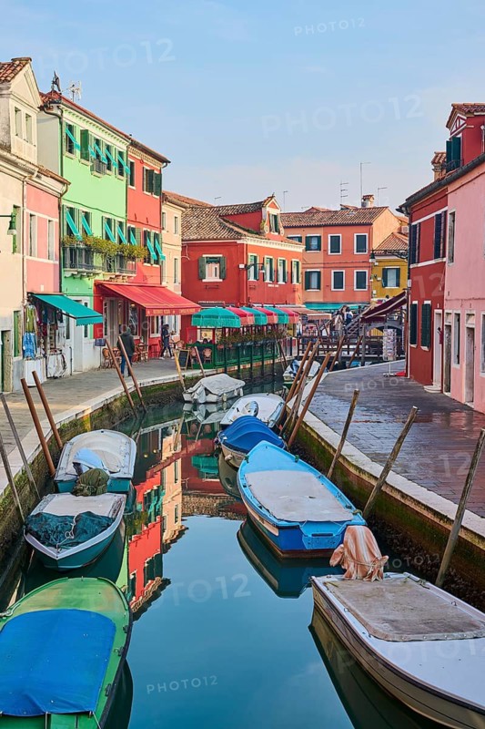 Colorful houses beside the waterway in between 'Fondamenta San Mauro' and 'Fondamenta degli Assassini' with boats lying in the water on the island of Burano, Italy