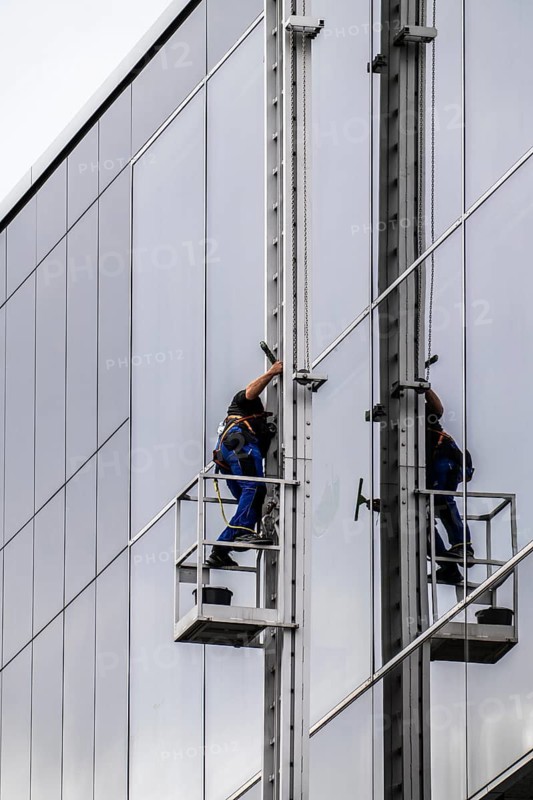 Window cleaner, facade cleaning, window cleaning, on a glass facade in Düsseldorf, ladder cage from the roof