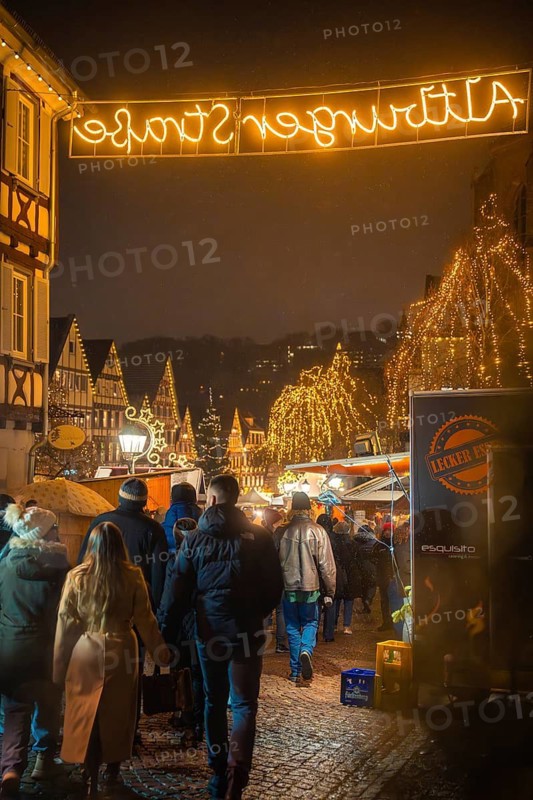 Festive Christmas market in the old town at night with illuminated trees and many visitors, Christmas market Calw, Black Forest, Germany