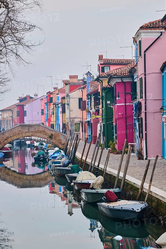 Colorful houses beside the waterway at 'Fondamenta di Terranova' with boats lying in the water on the island of Burano, Italy